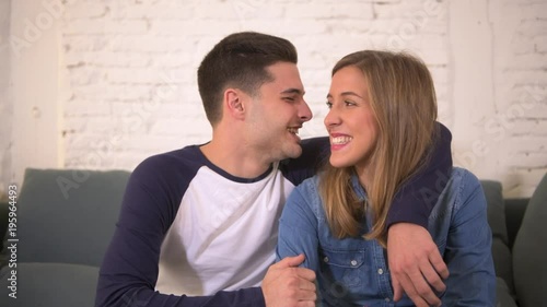 young happy and attractive Caucasian romantic couple or dating sitting at home sofa couch relaxed and smiling together cuddling  showing affection in boyfriend and girlfriend relationship lifestyle
