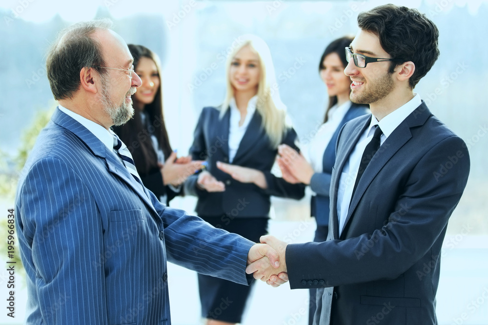 Meeting of two business partners at the presentation, greeting with a handshake Meeting of two business partners at the presentation, greeting with a handshake