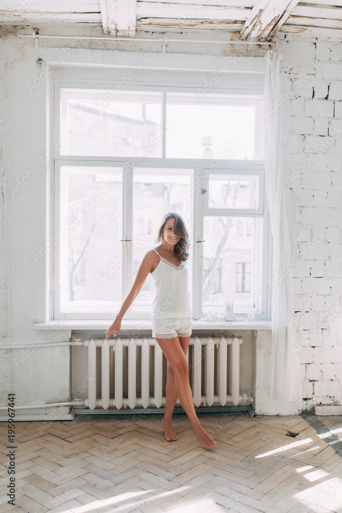 Portrait of pretty young girl on bed in modern Sunny apartment in the morning. Sipping and smiling, drinking coffee and lying on the floor Portrait of pretty young girl on bed in modern Sunny apartment in the morning. Sipping and smiling, drinking coffee and lying on the floor