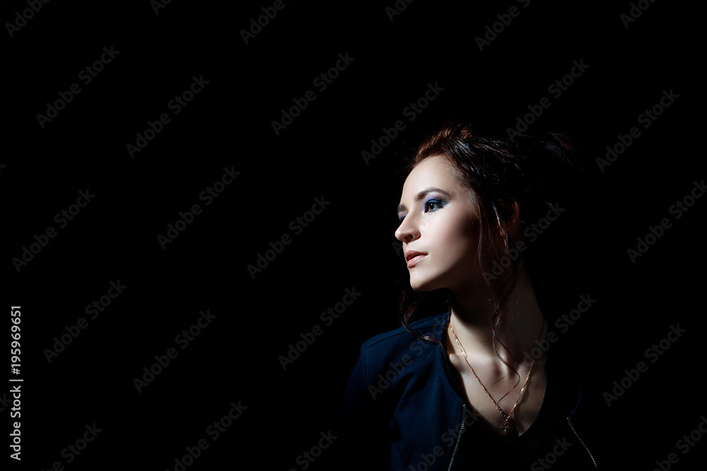 A girl in profile in fashion style on a black background in a low key with a place for text