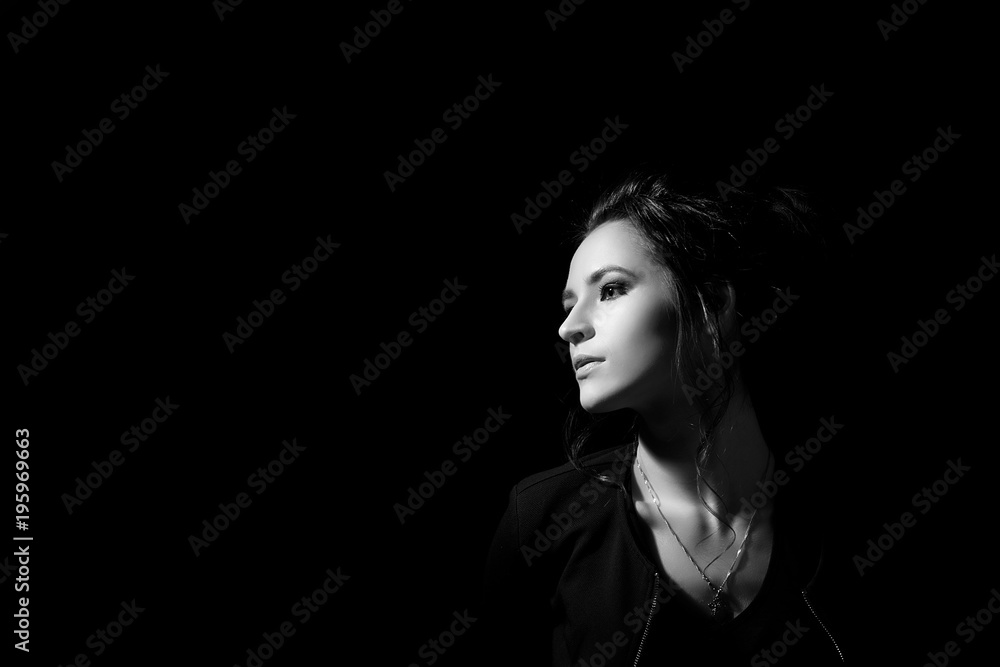 A girl in profile in fashion style on a black background in a low key with a place for an inscription