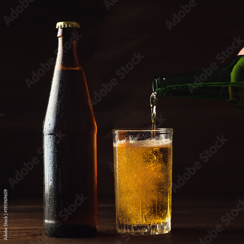 Wallpaper Mural Pouring foaming beer into glass mug with drops near cold beer bootle on wooden table, craft brewing concept Torontodigital.ca