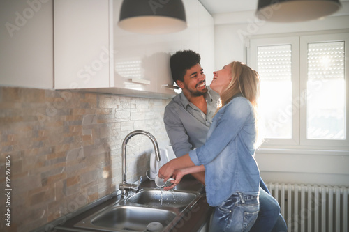 Tableau sur toile Young couple doing dishes in the kitchen and smiling