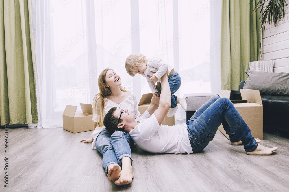 Family together happy young beautiful with a little baby moves with boxes to a new home - obrazy, fototapety, plakaty 