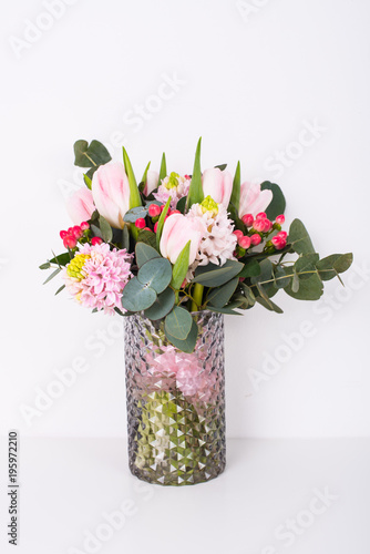 Boquet of pink flowers in vase by white wall