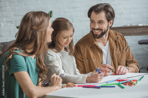 parents and daughter drawing with felt-tip pens at home