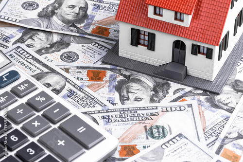 Close-up of a house model with calculator on dollar notes. Mortgage concept