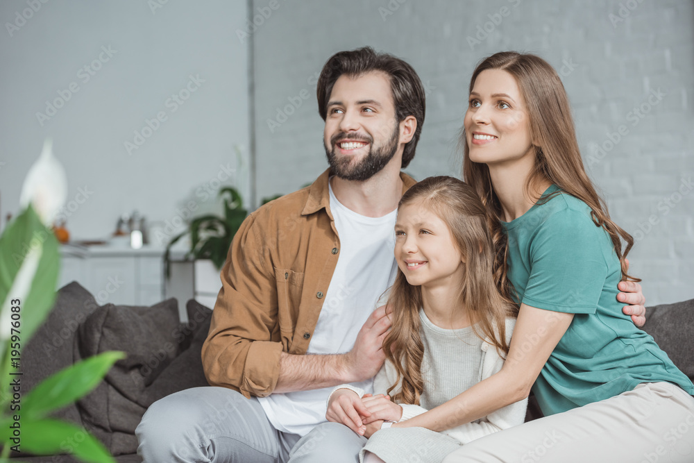 happy parents and daughter looking away at home