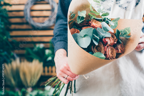 Florist at work on arragment flower bouquet on a wooden table photo