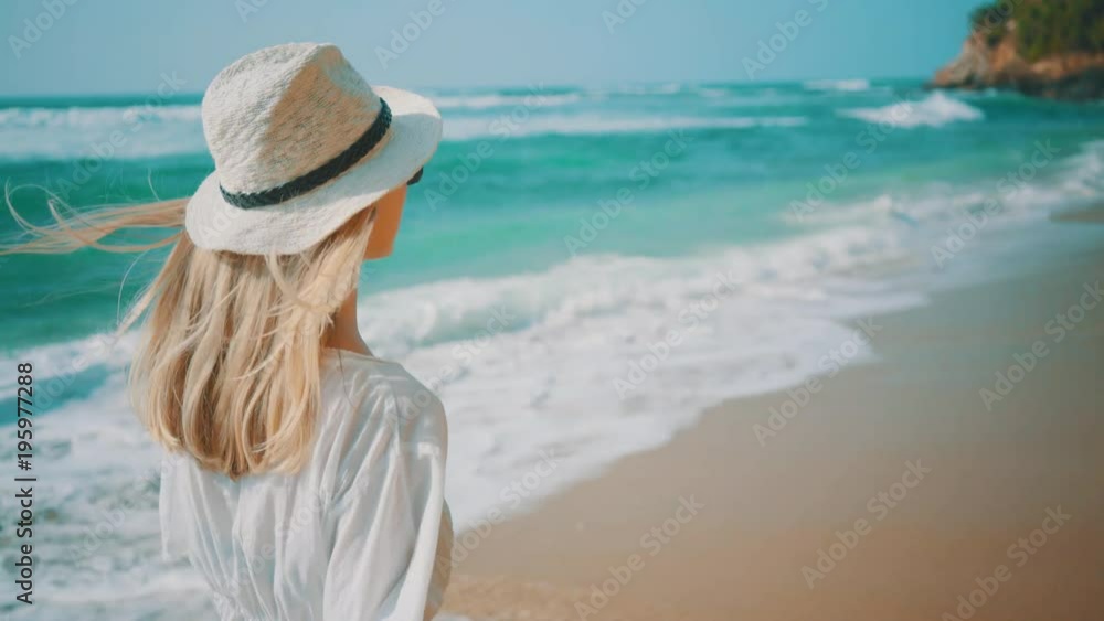Woman relaxing and walking on the ocean beach under blue sky in sunny day. Seascape view with palms. Woman relaxing and walking on the ocean beach under blue sky in sunny day. Seascape view with palms.