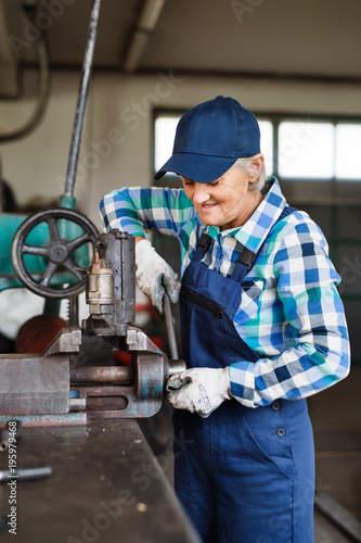 Senior female mechanic repairing a car in a garage.