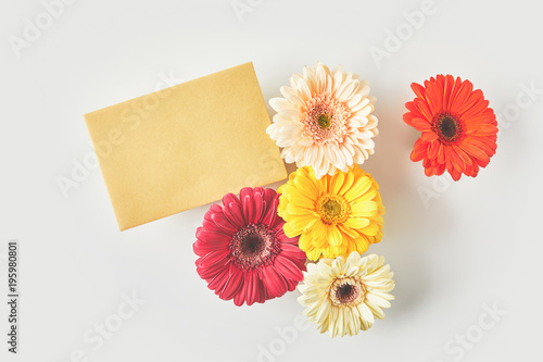 top view of blank card and beautiful gerbera flowers on grey