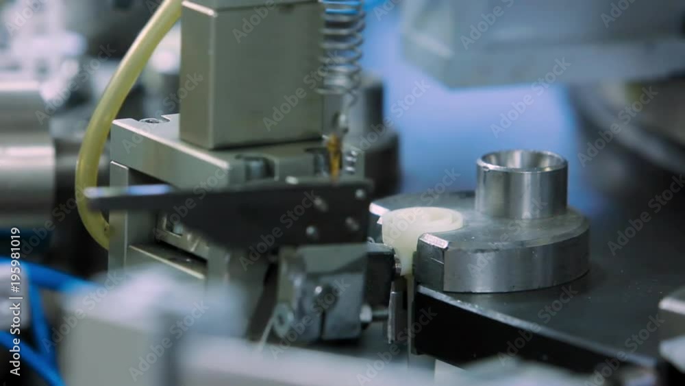 The machine inserts the lid on the production of droppers at the medical equipment factory The machine inserts the lid on the production of droppers at the medical equipment factory