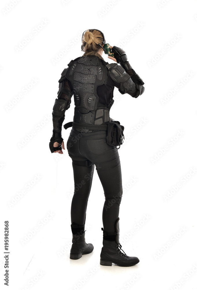 full length portrait of female soldier wearing black tactical armour, standing pose holding a walkie talkie, isolated on white studio background. full length portrait of female soldier wearing black tactical armour, standing pose holding a walkie talkie, isolated on white studio background.