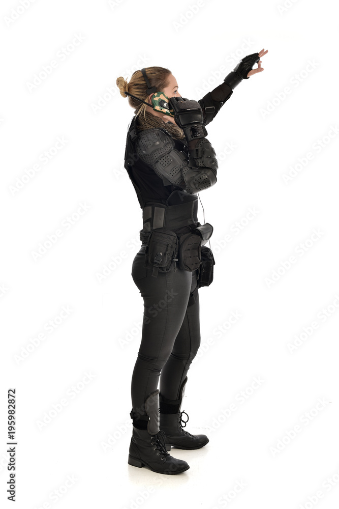 full length portrait of female soldier wearing black tactical armour, standing pose holding a walkie talkie, isolated on white studio background. full length portrait of female soldier wearing black tactical armour, standing pose holding a walkie talkie, isolated on white studio background.