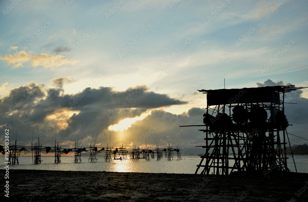 landskap kawasan penangkapan ikan pada waktu petang di tepi pantai yang menggunakan jaring dan ada pondok nelayan.