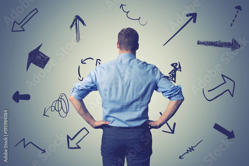 confused businessman with direction arrows. choosing the right way decision concept photo