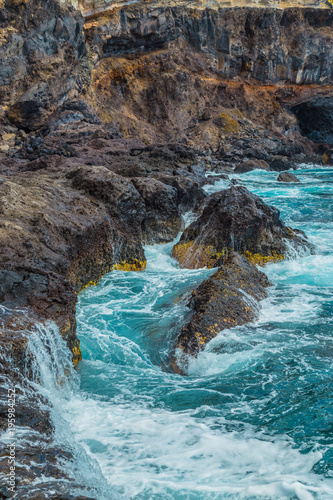 The blue waters of the Atlantic Ocean flowing into rocky cove off the coast of Tenerife. rocky shores of Canary Islands.
