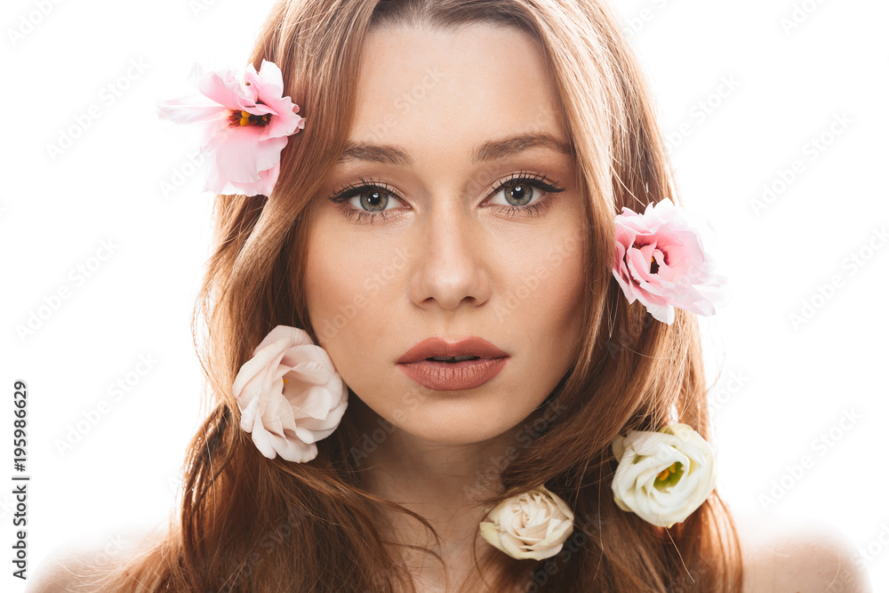Sensual young woman 20s wearing makeup looking on camera with beautiful eustoma flowers in her long auburn hair, isolated over white background Sensual young woman 20s wearing makeup looking on camera with beautiful eustoma flowers in her long auburn hair, isolated over white background