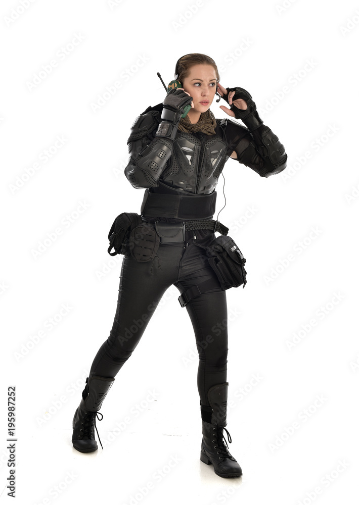 full length portrait of female soldier wearing black tactical armour,  standing pose holding a walkie talkie, isolated on white studio background.  Stock Photo | Adobe Stock