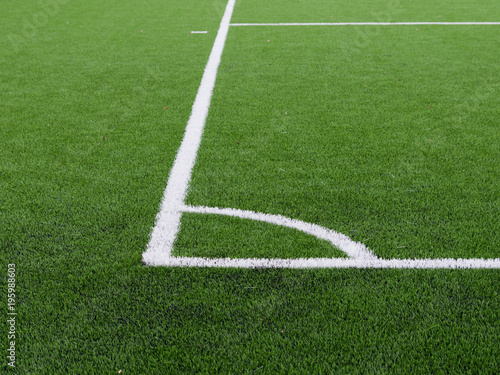 White lines on soccer field corner, artificial grass texture.