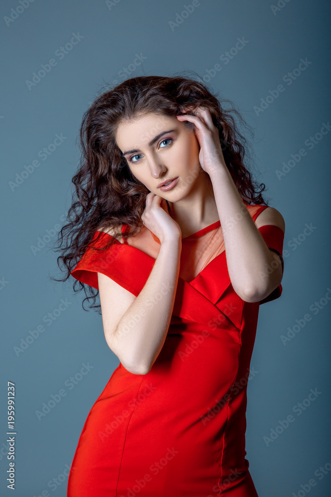 Long Hair. Beauty Sexy Cute Girl wearing in fashion red dress posing on ble gray background Long Hair. Beauty Sexy Cute Girl wearing in fashion red dress posing on ble gray background