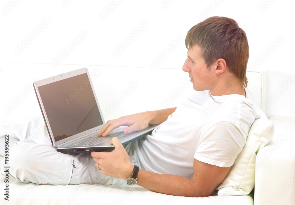 Very focused young man using laptop while sitting comfortably. Very focused young man using laptop while sitting comfortably.