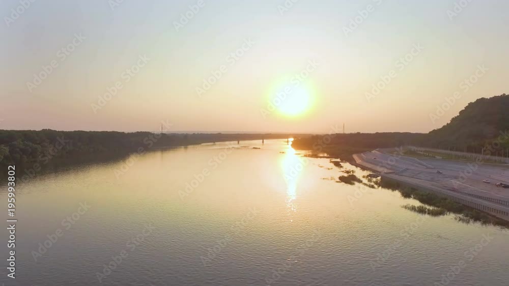 AERIAL: Flight over the river along the embankment to the railway bridge. Beautiful sunset landscape, summer, reflections on the water. AERIAL: Flight over the river along the embankment to the railway bridge. Beautiful sunset landscape, summer, reflections on the water.