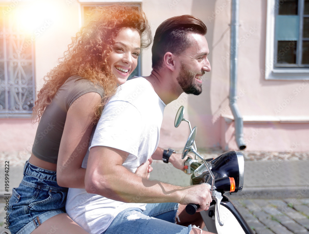 Happy cheerful couple riding vintage scooter outdoors.