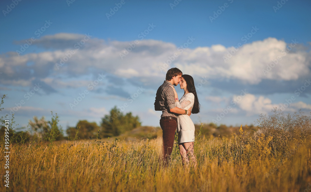 Couple in love gently embrace each other on the summer landscape background. Newlyweds in country style. Walk in the summer field.