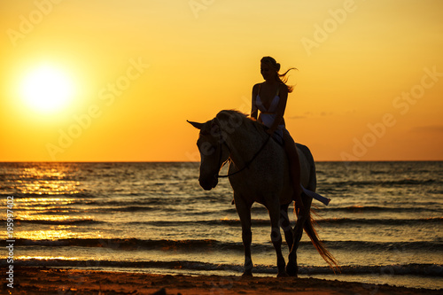 silhouette of a woman at sunset on horseback on the beach, camping, horseback riding photo