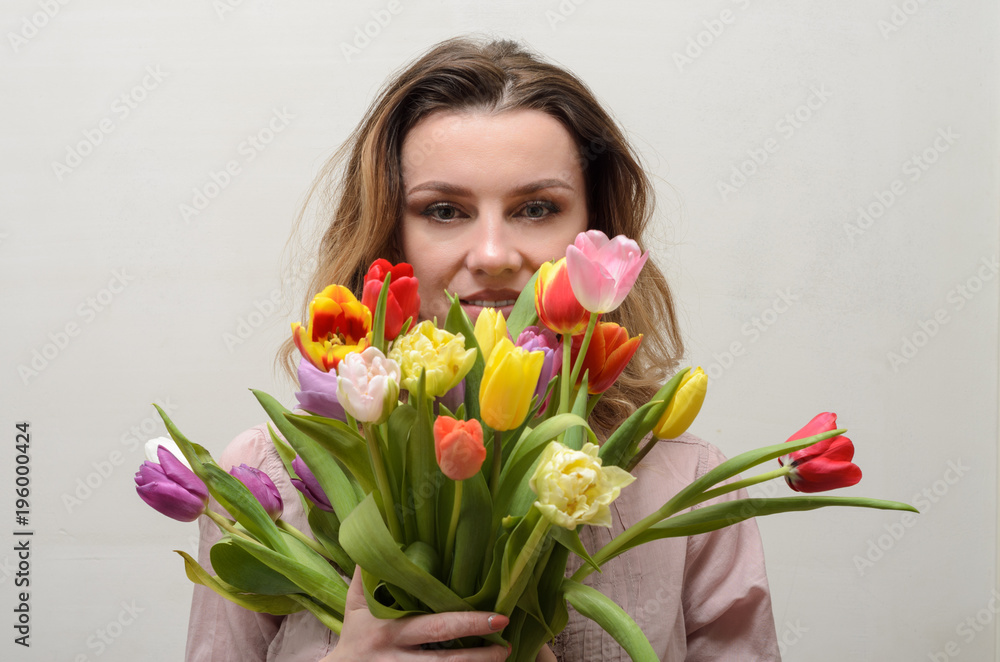 Young charming girl with a bouquet of flowers - multi-colored tulips Young charming girl with a bouquet of flowers - multi-colored tulips