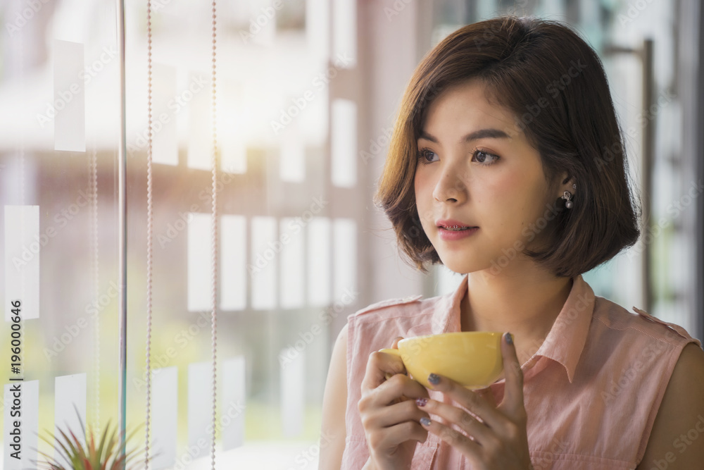 Young beautiful woman sitting at her desk holding cup of coffee Young beautiful woman sitting at her desk holding cup of coffee