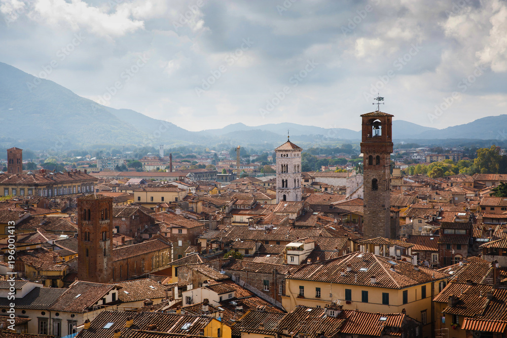 View of Torre Delle Ore from top of Guinigi Tower, Lucca, Tuscany, Italy. Scenic city panoramic overview picturesque travel postcard.