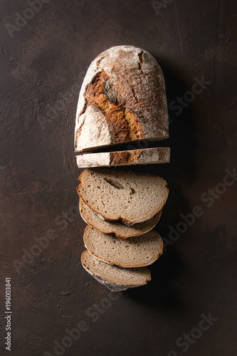 Canvastavla Loaf of fresh baked artisan sliced rye bread over dark brown texture background