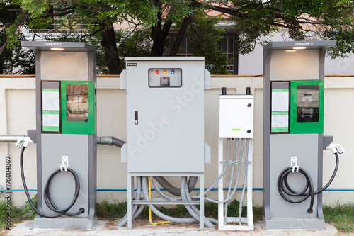 fast electric vehicle car charger with cable supply plugged and power supply box at EV station sites. EV car charging station in car park at supermarket ready to serve future automotive and city life.