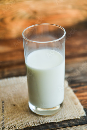 glass of milk with napkin on old wooden table