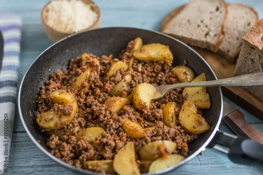 Savory mince and potato wedges in a frying pan - rustic dish Savory mince and potato wedges in a frying pan - rustic dish