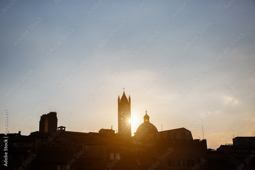 Picturesque silhouette view of Siena Cathedral Santa Maria Assunta (Duomo) at sunset golden hour, Tuscany, Italy. Scenic travel destiantion postcard.