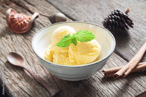 Homemade mango ice cream with mint in ceramic bowl on rustic wooden table