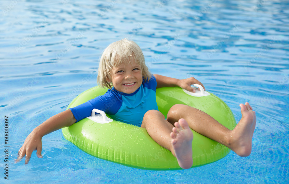 Happy little boy with  life ring has fun in the swimming pool