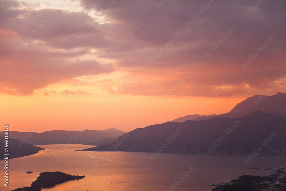 Amazing sunset landscape with sea, mountains, colorful pink, orange and purple cloudy sky. Beautiful The Boka Kotor Bay and Tivat view in Montenegro. Nature background.