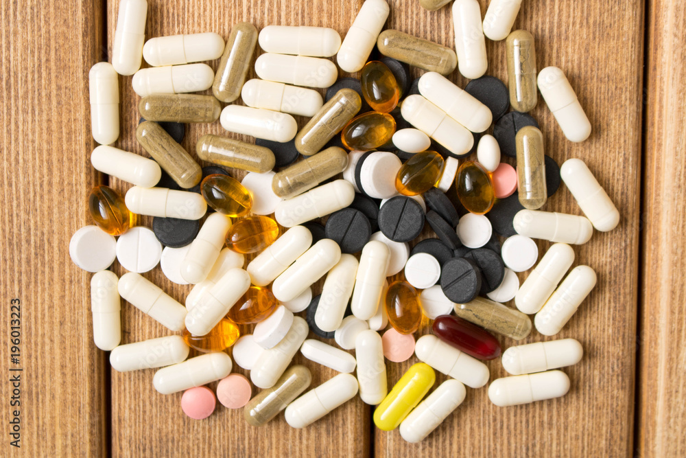 The pills are scattered on the table . On the background of wooden table The pills are scattered on the table . On the background of wooden table