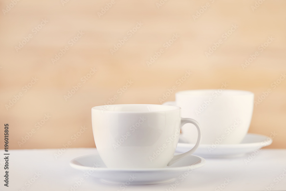 Two white porcelain teacups on white table show clean and simple design ideas, selective focus Two white porcelain teacups on white table show clean and simple design ideas, selective focus