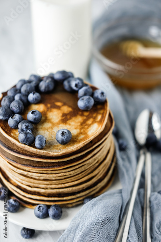 Homemade Chocolate Pancake with blueberries on a concrete gray background with milk and honey. Food photography of a healthy morning breakfast. Gauze Fabric.