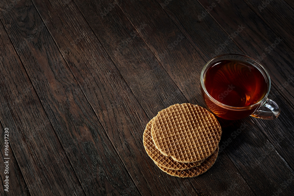 Cup of tea with a couple of waffles on a wooden background, top view, selective focus Cup of tea with a couple of waffles on a wooden background, top view, selective focus