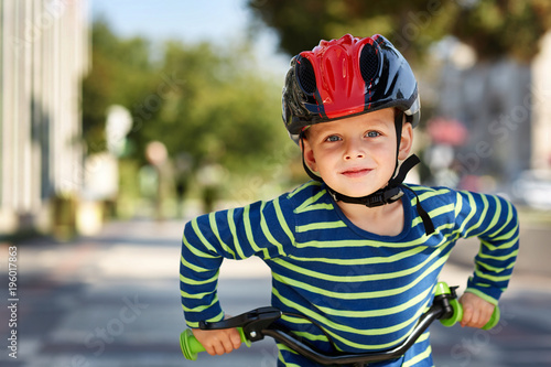 Portrait of a positive little boy on a bicycle outdoor, selective focus