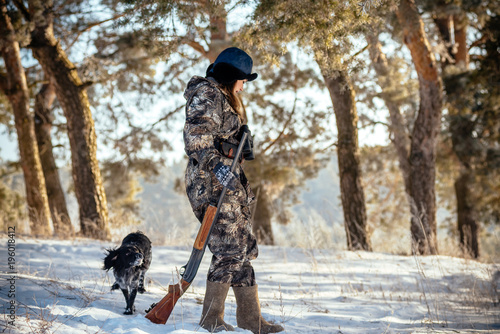 Girl hunter with binoculars in the forest, shows dog direction seeking mining. Concept of photo hunting with dogs, hounds.