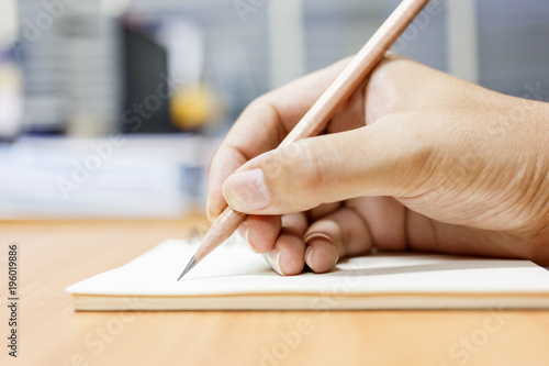 Man writing note with pencil on paper.