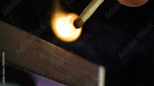 The match moves on the side of the matchbox and lights up. Close-up. Shallow depth of field. Slow motion.